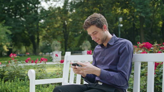 年轻人在公园里用手机玩游戏图片