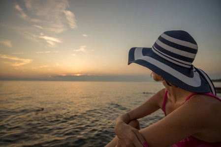 女人在一个时髦的稻草 sunhat 放松在海滩上寻找 o