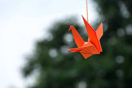 折纸橙色纸鸟挂在树上