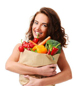 年轻女子拿着杂货纸购物袋里满是新鲜的蔬菜。饮食健康饮食观