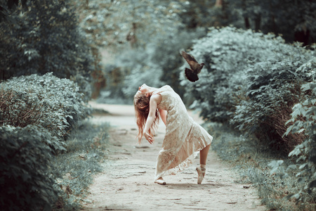 年轻的女孩在漂亮的衣服和普安特鞋子跳舞街与飞行的鸽子
