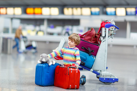 小小孩男孩与国际机场上的手提箱