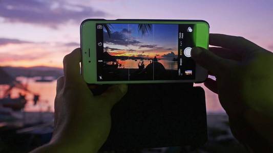 用手机拍照的人坐在沙滩上用手机拍照的女人的手的关闭照片