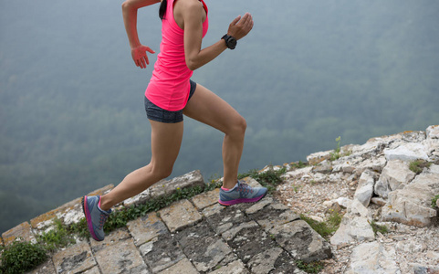 运动的妇女小径赛跑者跑在山顶上