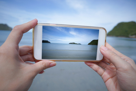 女人使用智能手机拍一张照片的大海
