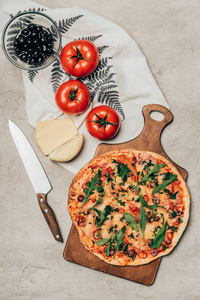 全比萨的木制切板与西红柿, 奶酪和橄榄在光的背景下