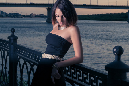 妇女在深切的悲痛之中,倚着栅栏在黄昏时分照片