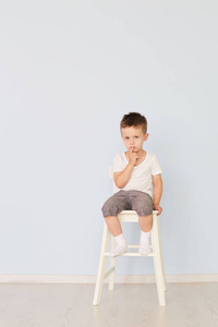 明亮的房间。穿着白衬衣的男孩坐在高高的椅子上