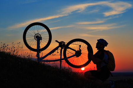 男子自行车修理自行车靠夕阳的剪影