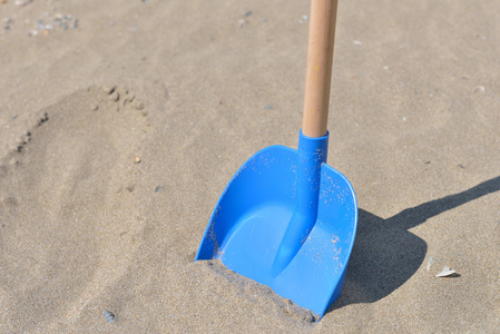 蓝色铲从塑料的木尾巴的孩子在沙子上
