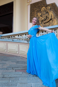 漂亮的女孩新娘年轻可爱的女人穿着长蓝色的衣服留在楼梯台阶上