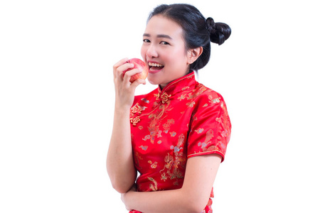 美丽的亚洲年轻女子的肖像穿中国传统旗袍或旗袍。吃红苹果, 孤立在白色背景, 健康, 中国新年庆典, 新年庆祝