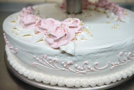 三级婚礼蛋糕装饰着鲜花, 站在桌子旁边的盘子和餐具