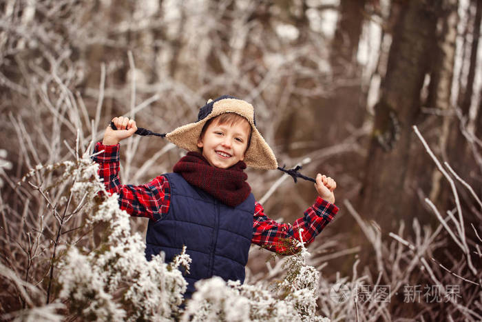 温暖的冬天森林里的肖像逗人喜爱的微笑的男孩