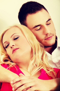 年轻夫妇睡在毯子下到沙发上