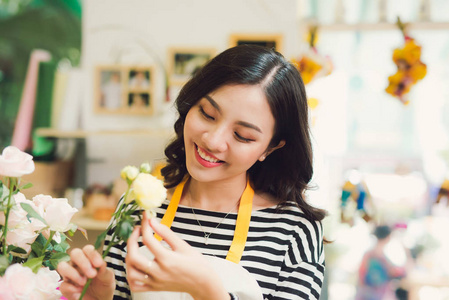 年轻漂亮的亚洲女孩花店照顾鲜花在工作场所