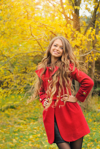 时尚女人穿着红色的外套，在秋天的公园