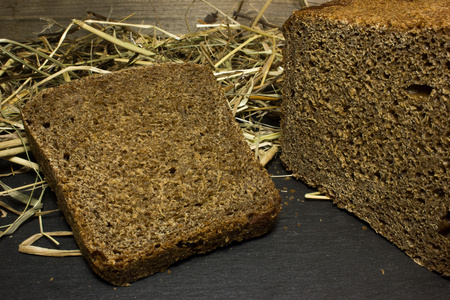 黑色背景下的干草的黑麦面包