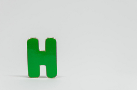 带有白色背景和选择性聚焦的绿色木制字母 H