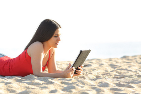 阅读电子书或平板电脑在海滩上的女孩