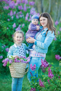 愉快的母亲和女儿与绿色苹果在盛开的紫丁香花园