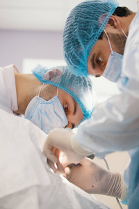 两名蓝袍外科医生在手术室里做手术