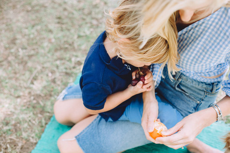 年轻的女人与她可爱的小儿子在夏季野餐放松与健康的食物