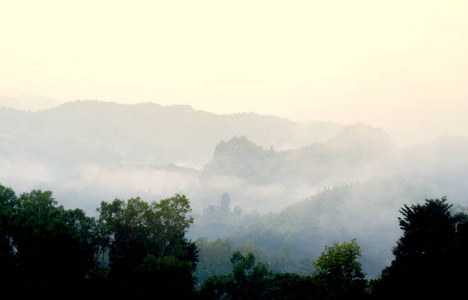 在薄雾的早晨, 山层的景色。雾在山谷中形成, 太阳照亮了白天