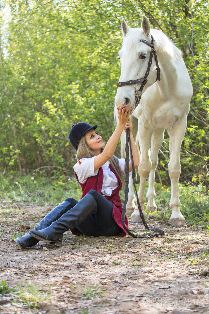 英俊的女人坐在她附近的棕色马地面