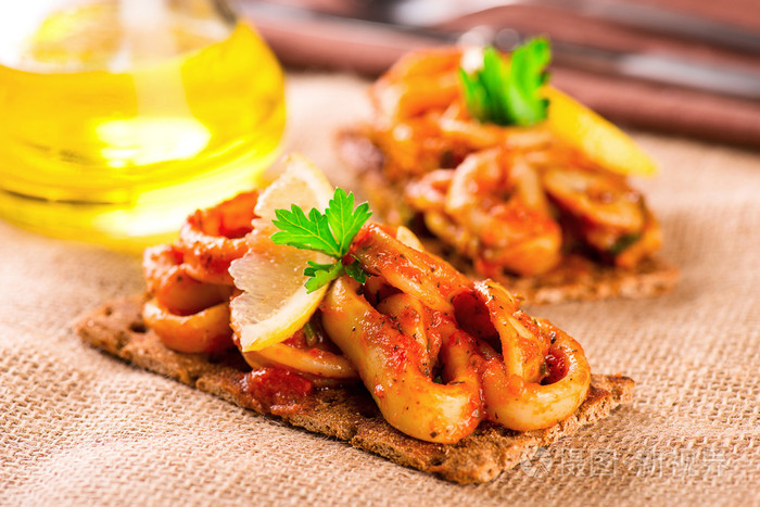 开胃菜辣番茄鱿鱼与柠檬在烤面包上