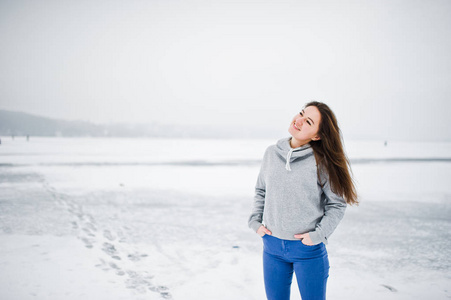 有趣的女孩穿在餐饮的毛衣和牛仔裤, 在冰冻的湖泊在 wi