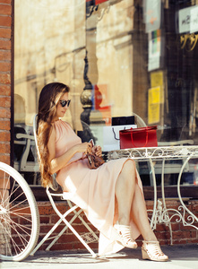 年轻漂亮的黑发女人购物坐在咖啡馆外面街道笑后