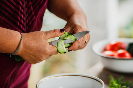 新鲜蔬菜沙拉的烹调过程, 健康的营养, 妇女的手切开黄瓜和蕃茄