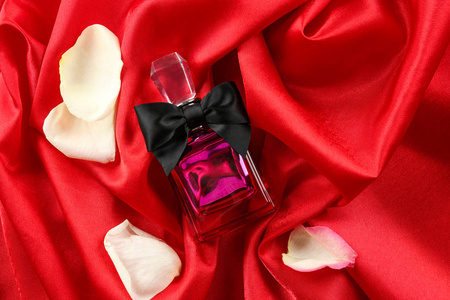 红丝绸上的香水瓶和玫瑰花瓣图片