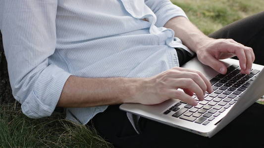 一名年轻男子使用笔记本电脑进行户外