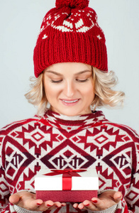 穿着暖和的毛衣和帽子的女人拿着圣诞礼物