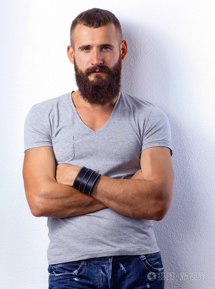 英俊的大胡子男人站,灰色的背景上孤立的肖像