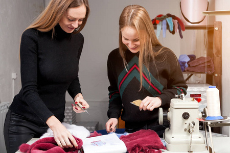 两个年轻的妇女商正在讨论如何正确地削减天然毛皮, 使妇女的毛皮大衣。妇女毛皮大衣的制作过程