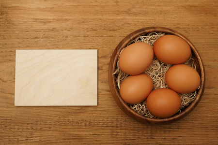 复活节桌。在木制的乡村餐桌上的鸡蛋的顶部视图。空木框招牌。复活节快乐