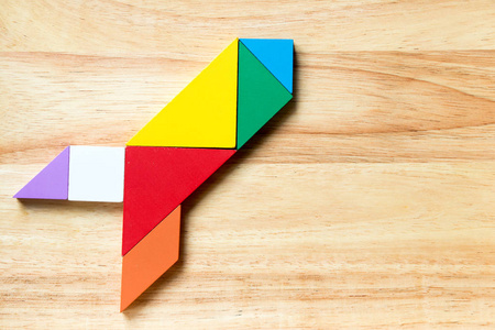 在木质背景下火箭或导弹形状的彩色七巧板拼图照片