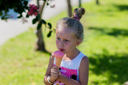 女孩吃冰激淋华夫格杯在树荫下角夏季的一天