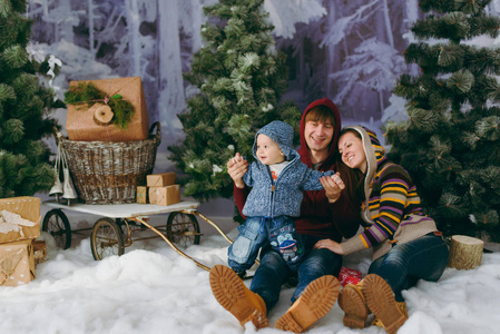 年轻顽皮的快乐的父母与一个可爱的小男婴在12月