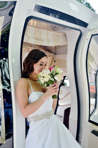 新娘在婚纱礼服与花束和蕾丝面纱在车上