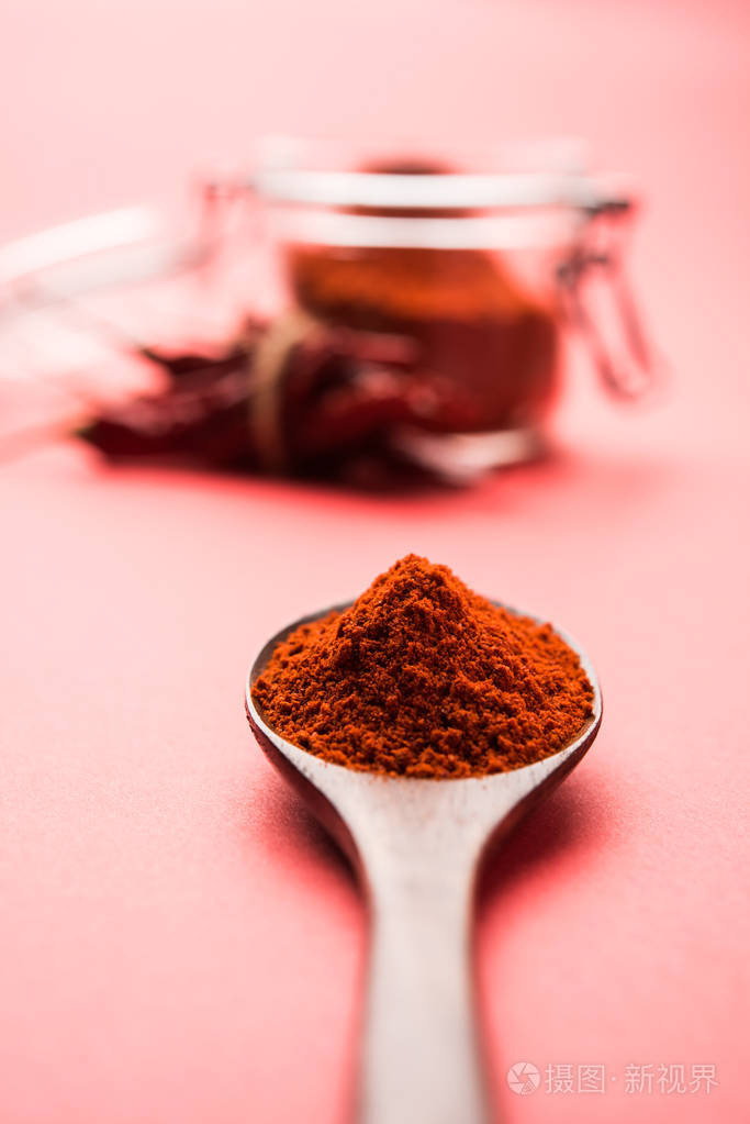 一个碗与干燥红色辣椒在五颜六色的背景或一堆红色辣椒粉末在平原背景