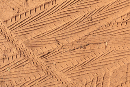 在阳光下的沙子上的宏观纹理轮胎印
