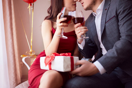 美丽的情侣在餐厅庆祝情人节, 喝葡萄酒, 分享礼物, 享受彼此