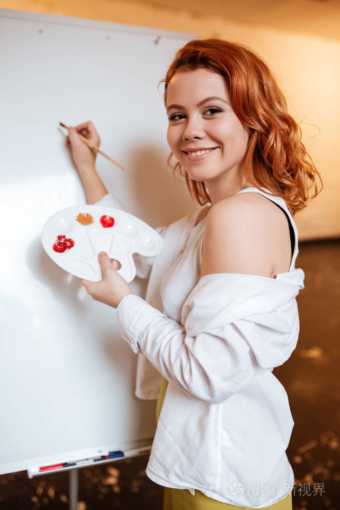 微笑美女画家绘画与油画颜料上空白