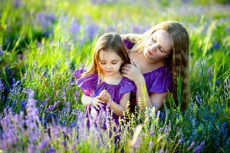 一个年轻漂亮的女人带着她可爱的小女儿在阳光明媚的夏日里漫步在麦田