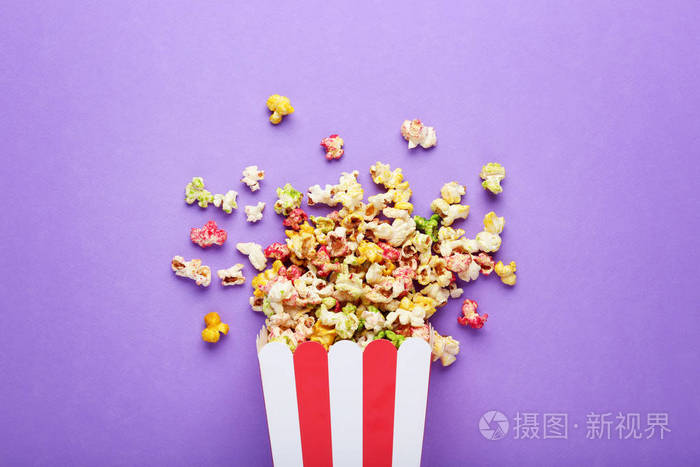 紫色背景下带条纹桶的甜爆米花