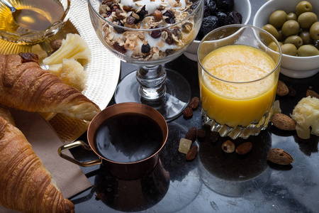 早餐什锦的酸奶 麦片 咖啡 果汁 牛角包 橄榄。开胃菜拌早上菜。健康 新鲜 美味的食品，在深色背景上